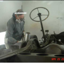 Worker painting halftrack interior in booth