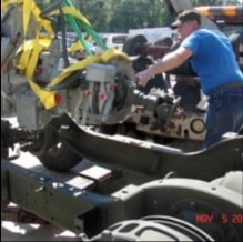 Man in blue shirt guiding engine into halftrack frame