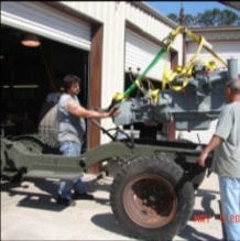 Workers guiding engine into halftrack frame