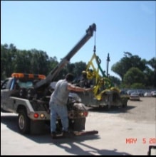 Tow truck crane positioning engine over halftrack