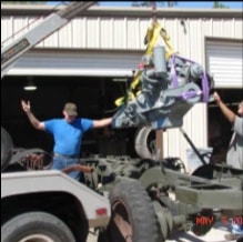 Engine suspended by crane being lowered into halftrack